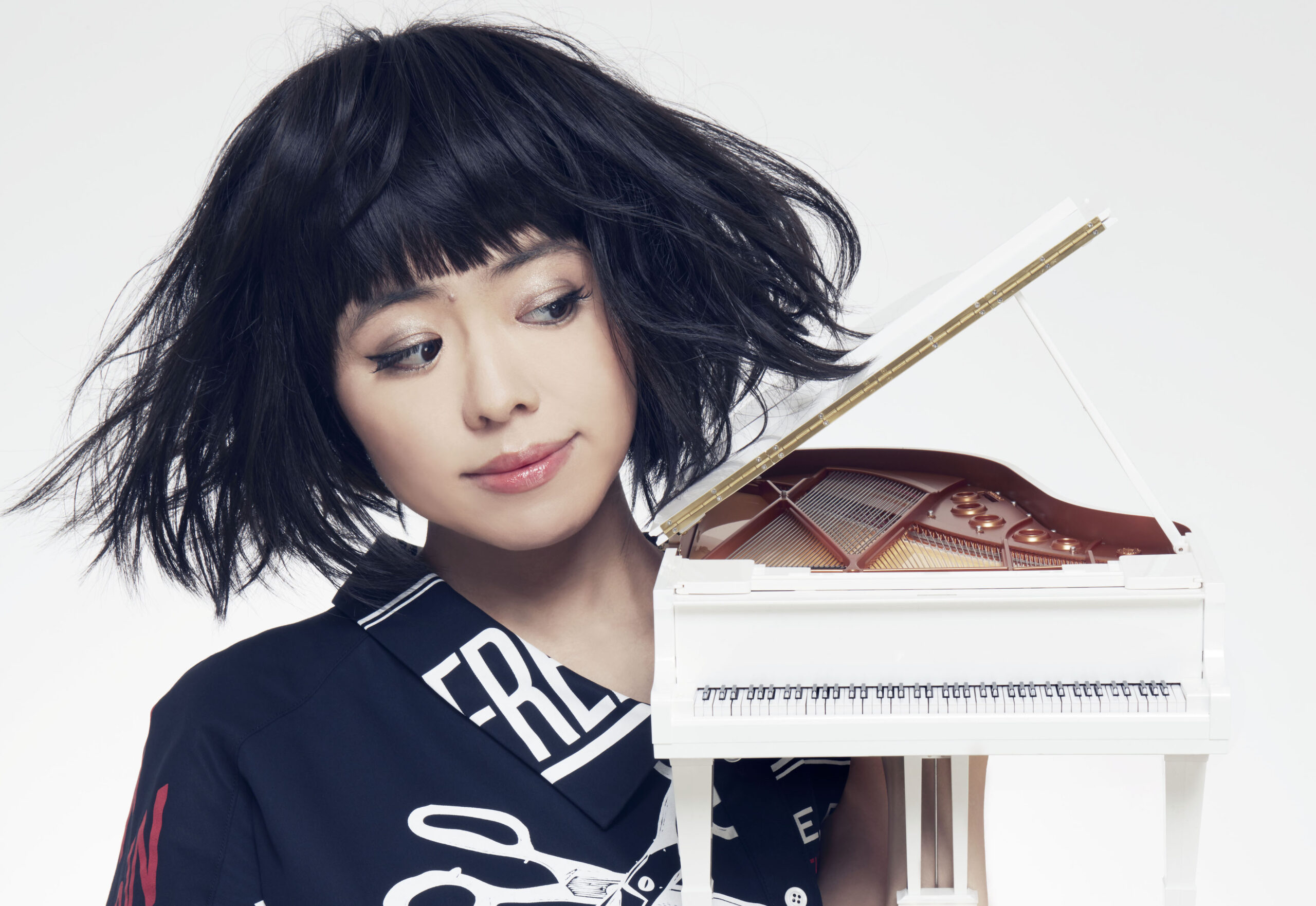Hiromi holds a toy piano and looks at it wistfully. Photo by Muga Miyahara.