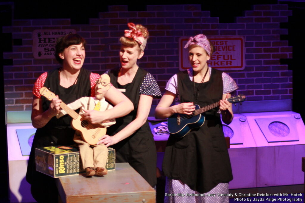 Performers from Axis Theatre hold Mr. Hatch puppet and play ukulele. Photo by Jayda Paige.