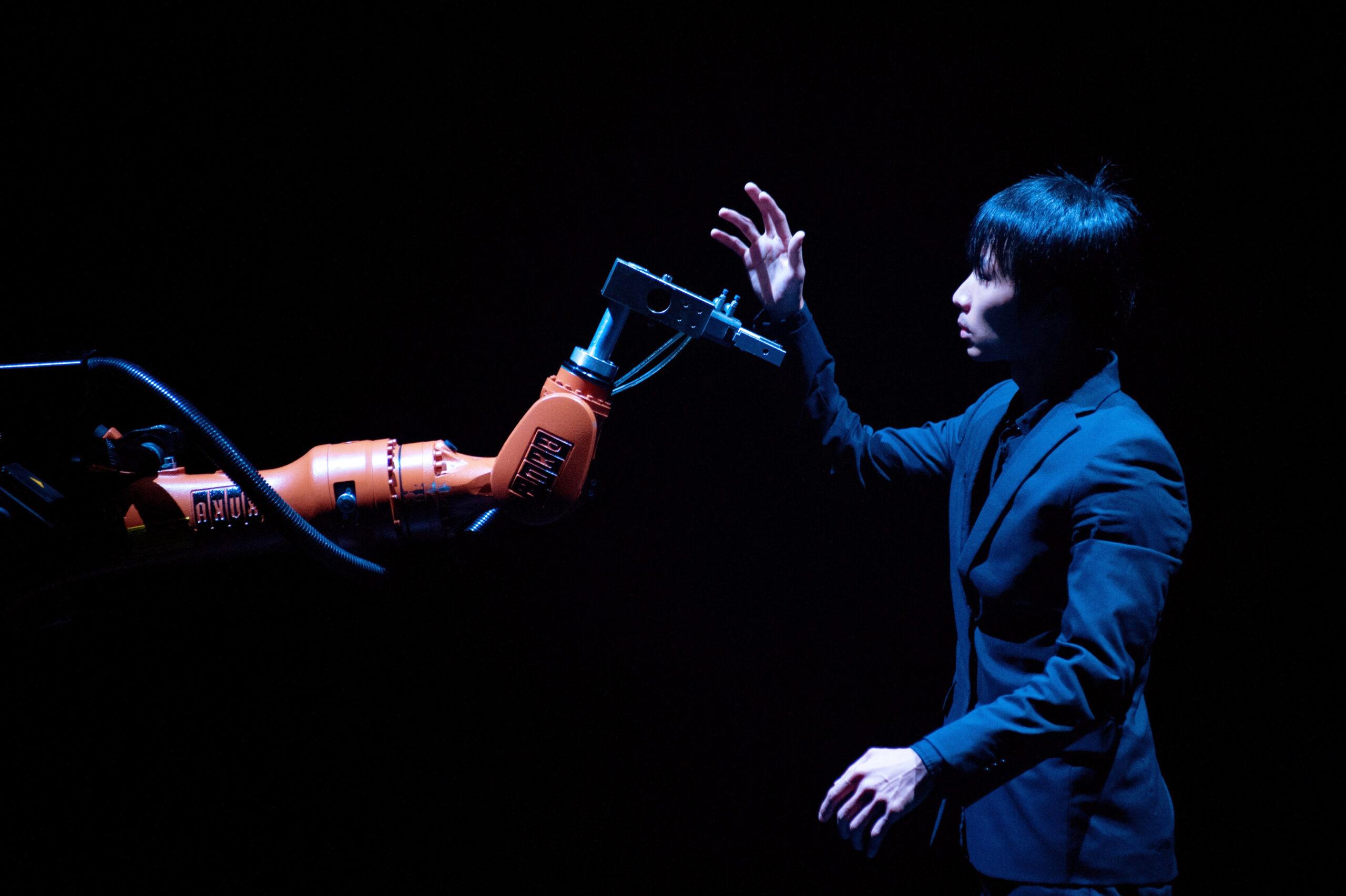 Huang Yi and another dancer on stage with a light from KUKA the robot