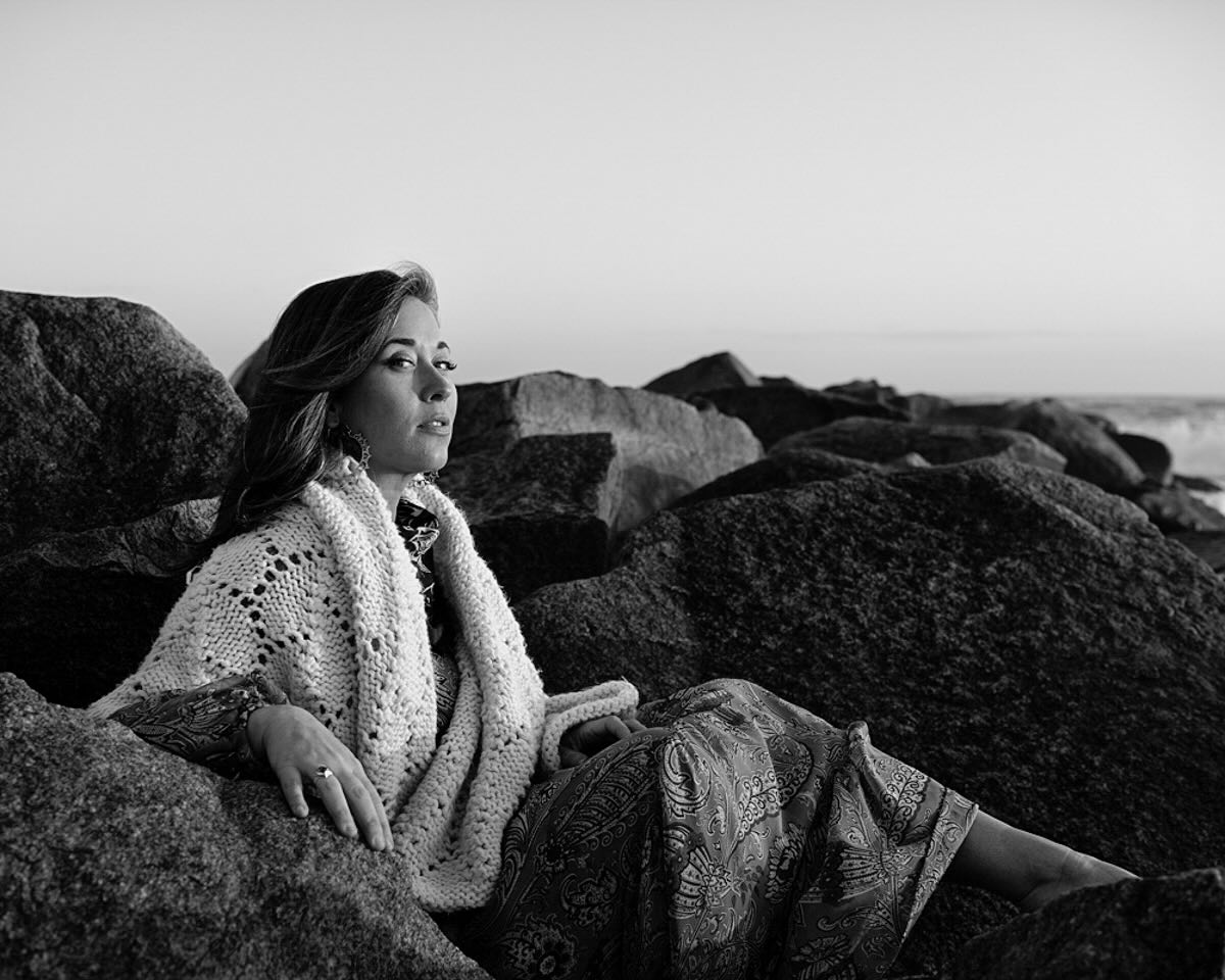 Rebekah Todd sits on rocks, looking directly at the camera.