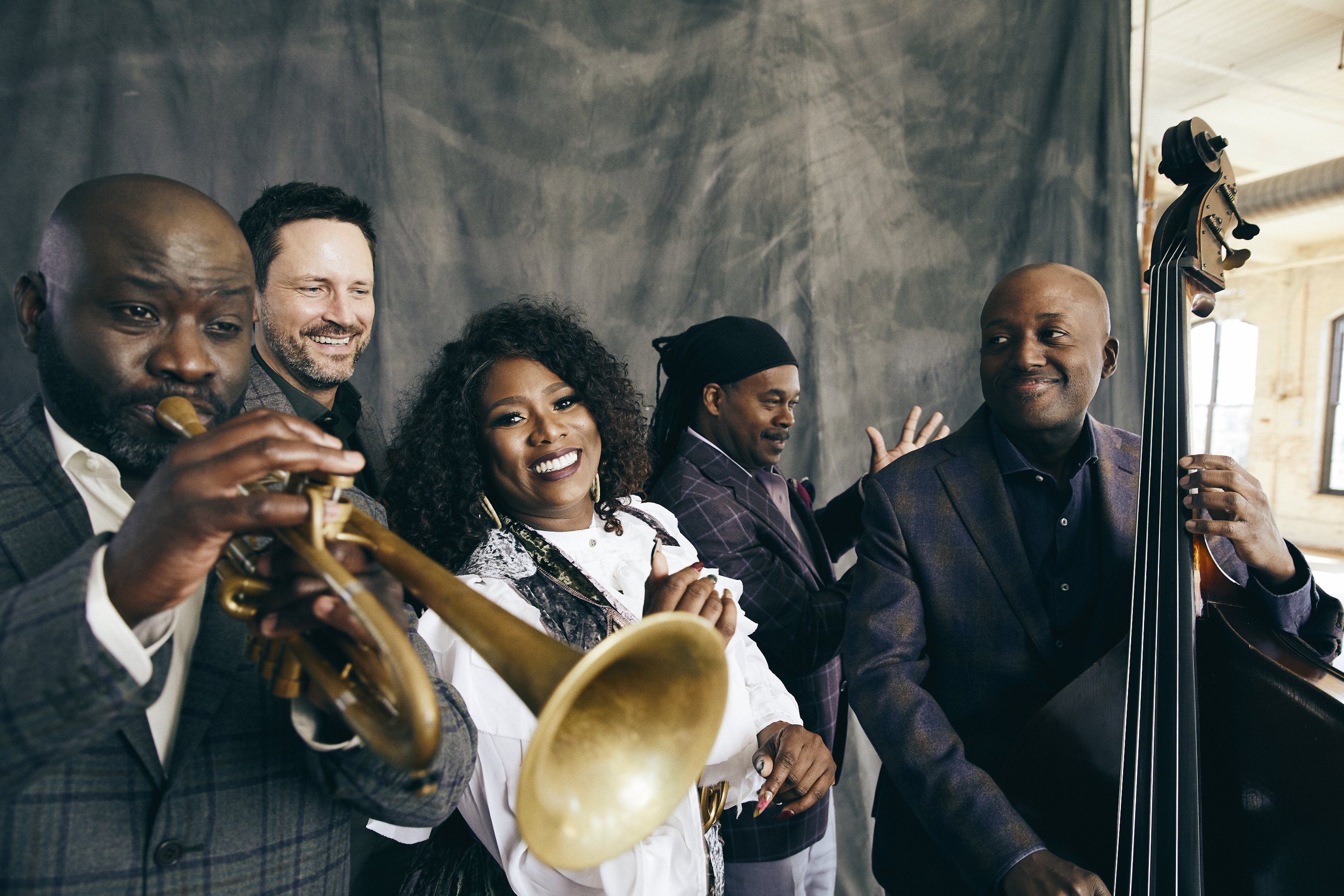 Members of Ranky Tanky band gather with their instruments, a trumpet at the forefront.
