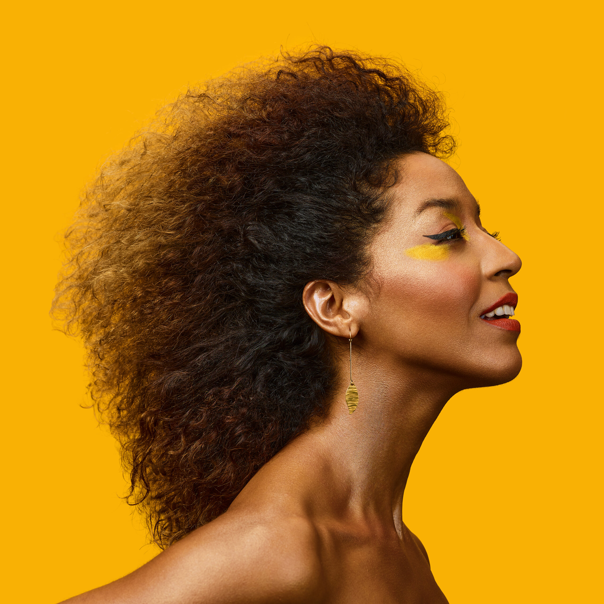 Yilian Canizares smiles in profile against yellow background.